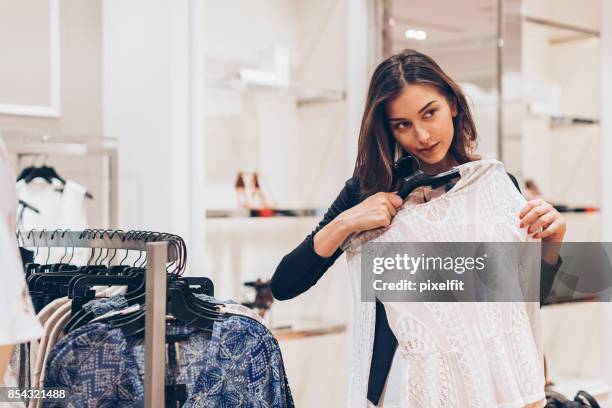 mujer joven eligiendo ropa en la tienda - lace dress fotografías e imágenes de stock