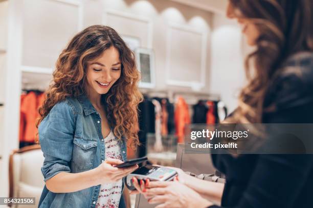 pago de teléfono inteligente en un retail de moda - pago por móvil fotografías e imágenes de stock