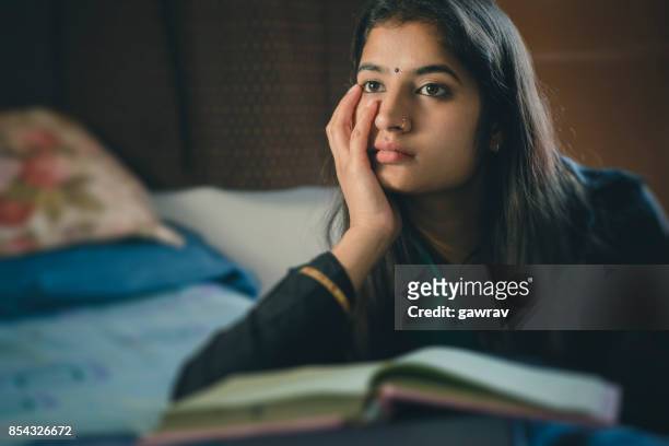 education: young woman thinking while studying. - loneliness stock pictures, royalty-free photos & images