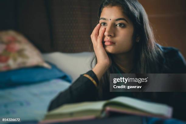 education: young woman thinking while studying. - bindi stock pictures, royalty-free photos & images