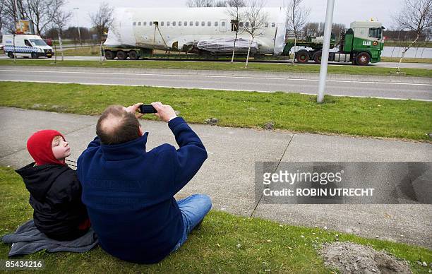 People watch as the wreck of a Turkish airlines Boeing 737-800 that crashed near Amsterdam two and a half weeks ago is transported to Schiphol...