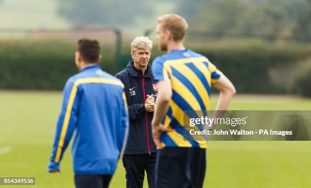 Arsenal's manager Arsene Wenger watches as Mesut Ozil and Per Mertesacker walk out for the start of training during a training session at London...