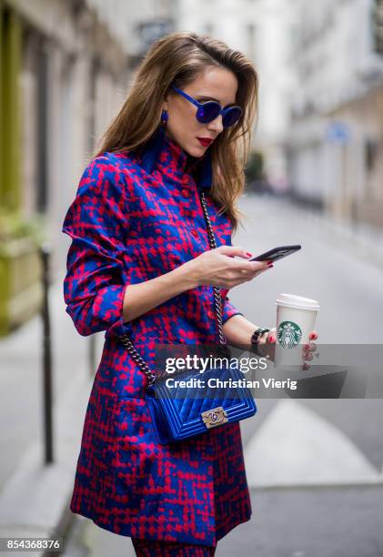 Alexandra Lapp with phone and Starbucks coffee to go wearing a two-piece in red and blue by Riani, a blue lacquer Chanel Boy bag, blue sunglasses by...