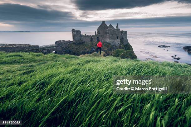 tourist at dunluce castle, northern ireland - dunluce castle stockfoto's en -beelden