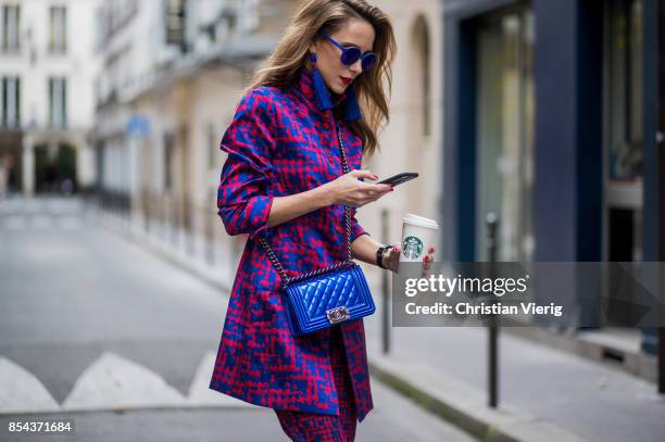 Alexandra Lapp with phone and Starbucks coffee to go wearing a two-piece in red and blue by Riani, a blue lacquer Chanel Boy bag, blue sunglasses by...