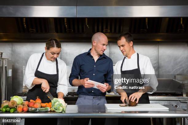 restaurang manager fungerar med hans professionella kockens - chef in kitchen bildbanksfoton och bilder