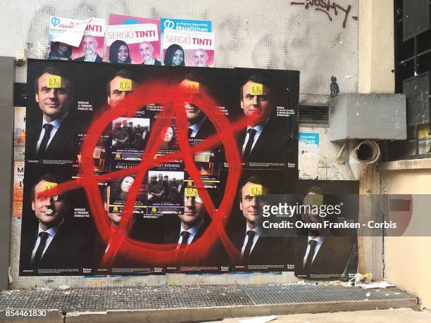 Series of posters displaying the portrait of French President Emmanuel Macron are daubed with a circle-A in the 19th arrondissement on September 26,...