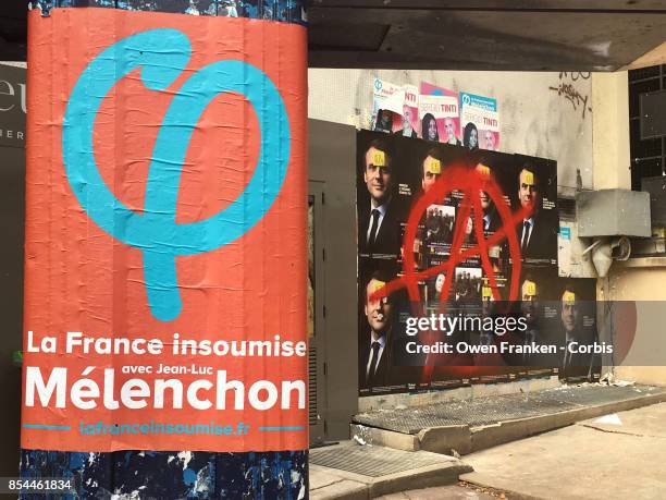 Poster for left-wing politician Jean-Luc Melanchon is displayed near protest graffiti covering a series of portraits of French President Emmanuel...
