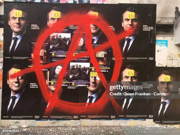 Series of posters displaying the portrait of French President Emmanuel Macron are daubed with a circle-A in the 19th arrondissement on September 26,...