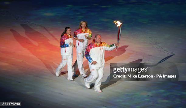 Russian wrestler Alexander Karelin carries the torch alongside Maria Sharapova and Yelena Isinbayeva during the Opening Ceremony for the 2014 Sochi...