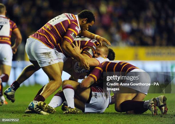 Wigan Warriors' Joe Burgess is tackled by Huddersfield Giants' Leroy Cudjoe , Chris Bailey and Shaun Lunt during the First Utility Super League match...