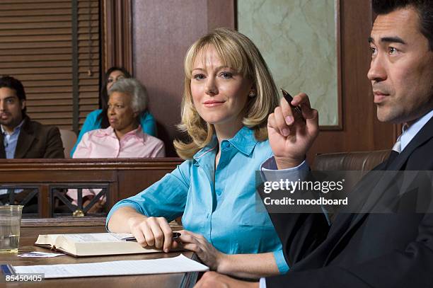 defense lawyer with client in court - prosecuting attorney stock pictures, royalty-free photos & images