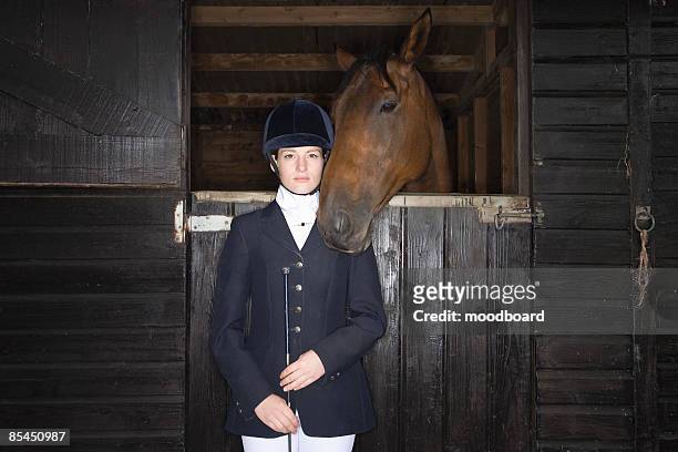 portrait of female horseback rider with horse in stable - riding hat fotografías e imágenes de stock