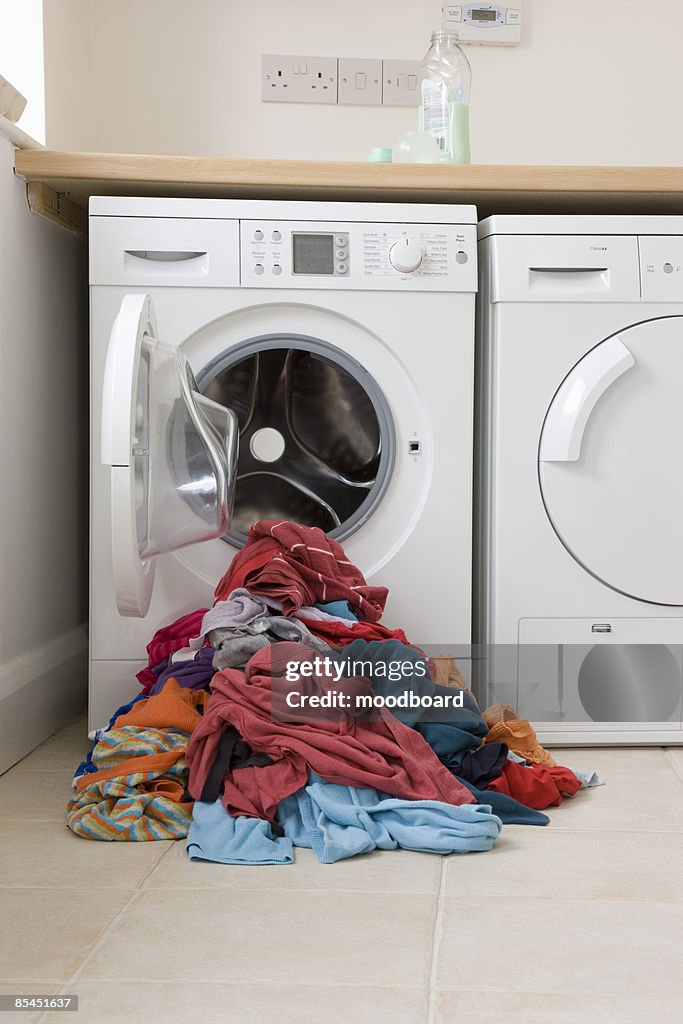 Pile of clothes in front of washing machine