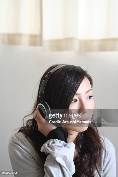 young woman listening music on headphones - atsushi yamada stock pictures, royalty-free photos & images