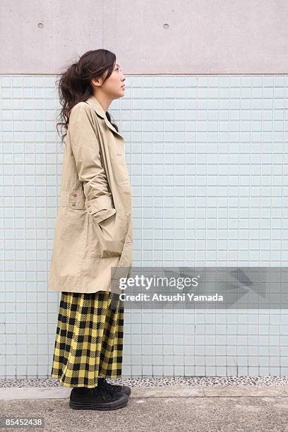 young woman standing by wall,side view - atsushi yamada stock pictures, royalty-free photos & images