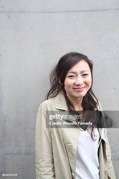 young woman standing against wall,smiling - atsushi yamada stock pictures, royalty-free photos & images