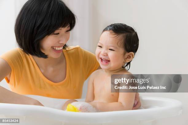 asian mother washing her daughter in bathtub - bath girl stockfoto's en -beelden