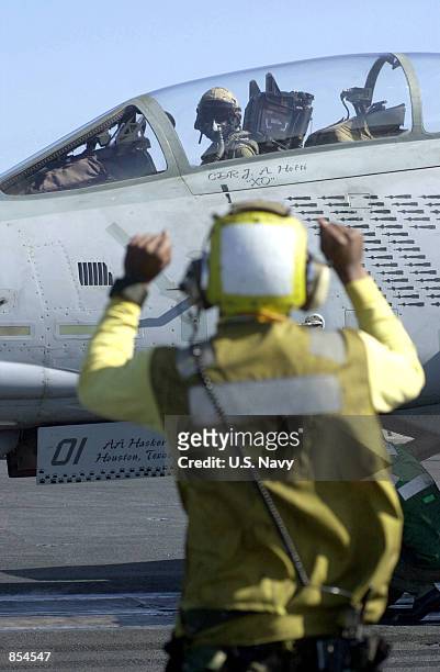 Navy flight deck director gives hand signals to a pilot as he lines up his F-14D "Tomcat" from the flight deck of the USS Carl Vinson December 5,...