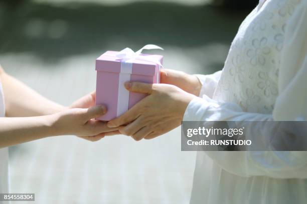 daughter giving present to mother in the park - mature woman daughter stock pictures, royalty-free photos & images