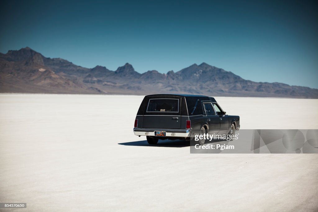 Classic funeral hearse drives on the salt flats in Utah USA