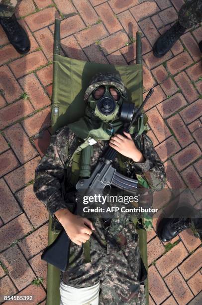 South Korean soldier wearing a gas mask participates in a decontamination training at a stadium in Seoul on September 27, 2017. The training is...