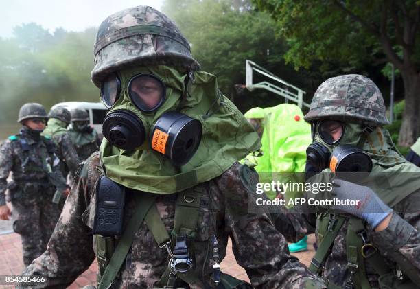 South Korean soldiers wear gas masks during a decontamination training at a stadium in Seoul on September 27, 2017. The training is designed to train...