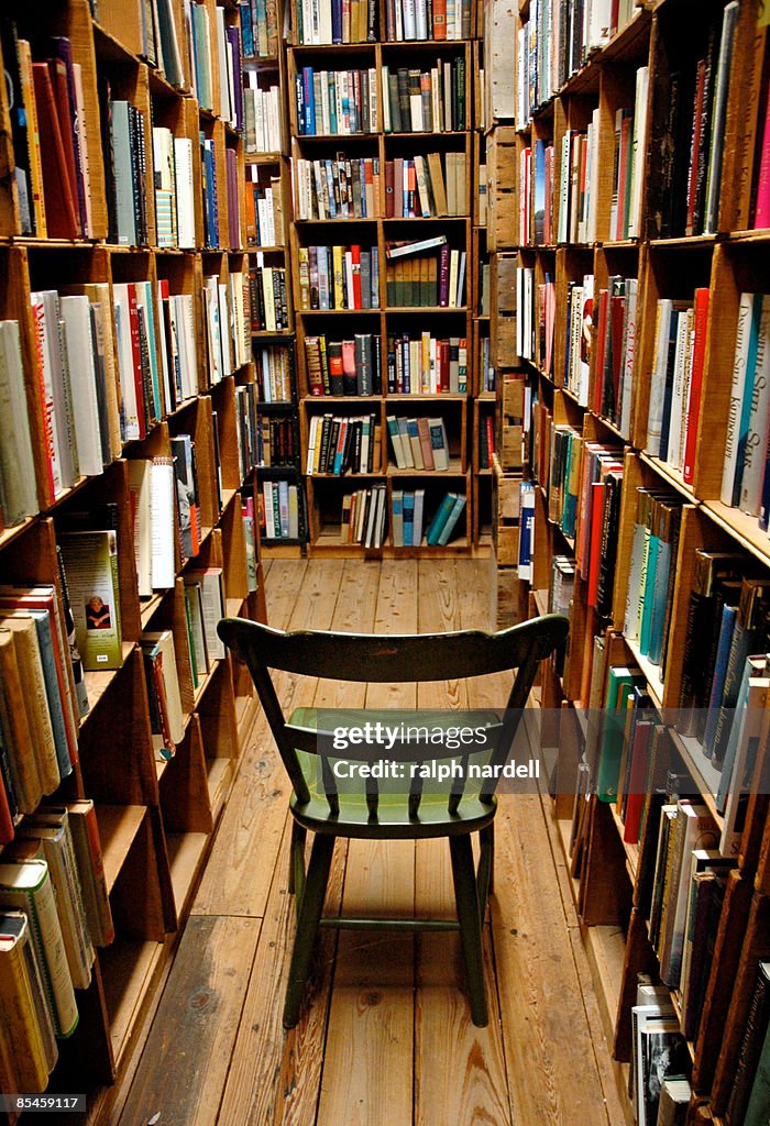 Used bookstore and empty chair amid bookshelves