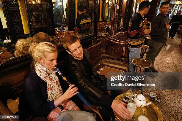 Tourist couple relax with a sheesha, also known as a water-pipe or nargilla, fresh lemonade and mint tea at the el-Fishawi coffee shop, made famous...