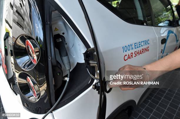 This photograph taken on September 26, 2017 shows a staff member displaying the charging compartment of an electric Bluecar ahead of the launch of a...