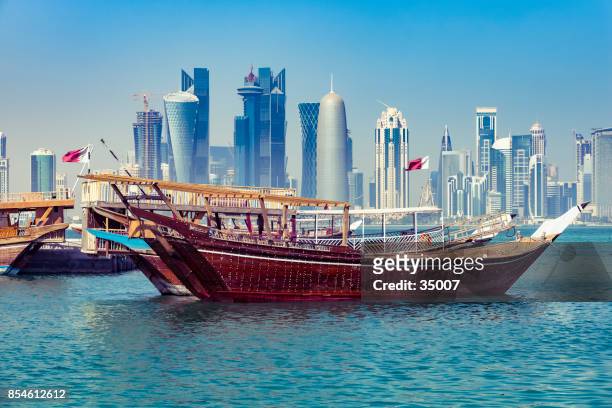 dhow tradicional con moderno skyline en doha, qatar - doha fotografías e imágenes de stock