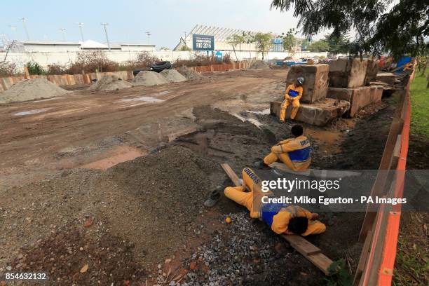Olympic venues under construction for the Rio 2016 Games as a site workers take a nap in the foreground