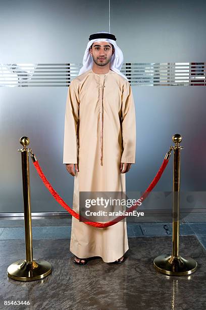 profile of an emirati man standing behind a stanchion. - stanchion stock pictures, royalty-free photos & images