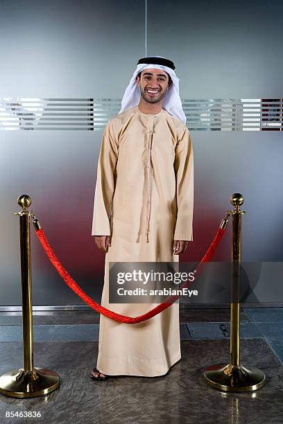 profile of an emirati man standing behind a stanchion. - stanchion stock pictures, royalty-free photos & images