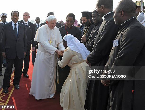 Pope Benedict XVI , flanked by Cameroonian President Paul Biya , is greeted by a Cameroonian nun on arrival at the airport in Yaounde on March 17,...