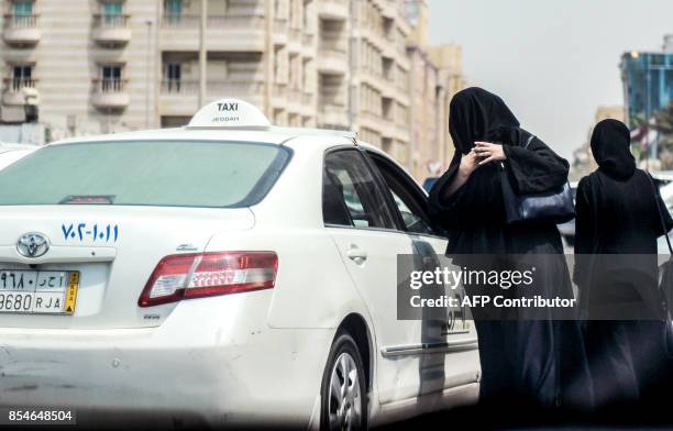 Saudi woman prepares to get into a taxi on a main street in the Saudi coastal city of Jeddah on September 27, 2017. Saudi Arabia will allow women to...