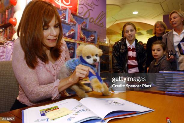 Photographer Lara Jo Regan guides her dog Mr. Winkle as he gives a paw print to a new calander December 14, 2001 at a signing at FAO Schwartz in New...