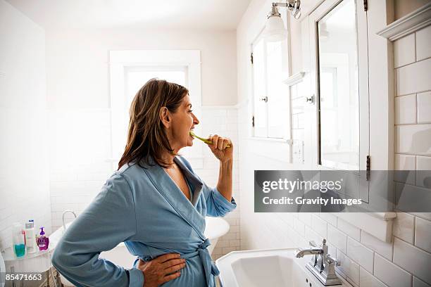 woman brushing teeth, side view - lavarsi i denti foto e immagini stock