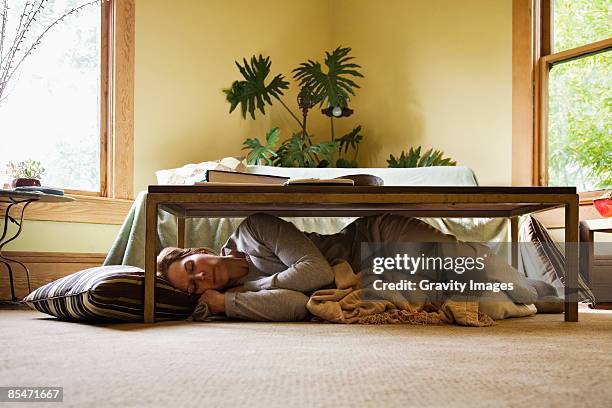 woman sleeping under coffee table - under sofa stockfoto's en -beelden