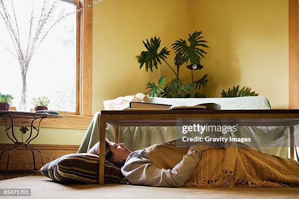 woman sleeping under coffee table - under sofa stockfoto's en -beelden