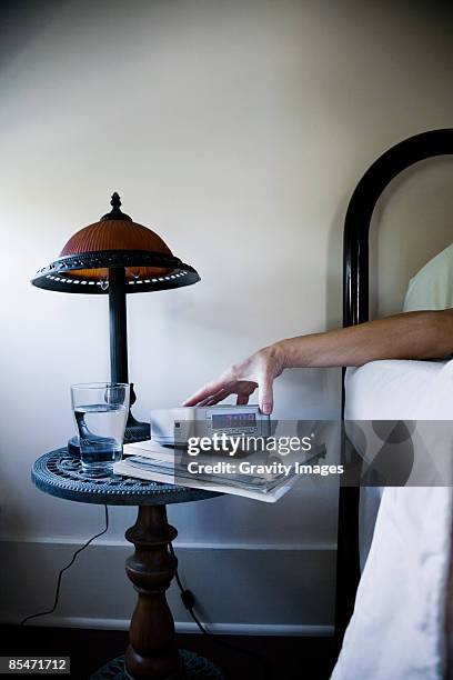 woman lying in bed, holding alarm clock - alarm clock on nightstand stock pictures, royalty-free photos & images