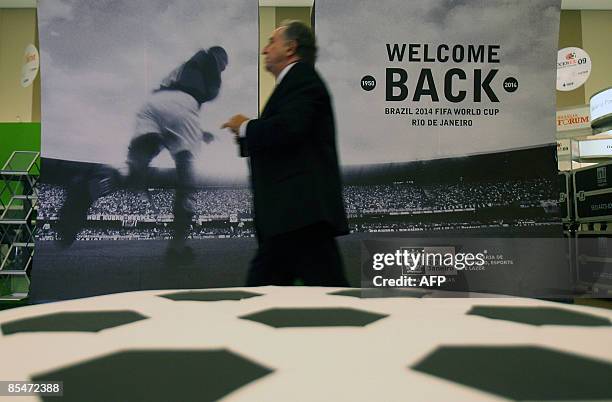 Man walks in front of a huge poster promoting Brazil 2014 FIFA World Cup during the Soccerex Brasilia Forum 2009 opening ceremony on March 17, 2009...