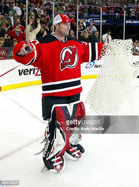 Goaltender Martin Brodeur of the New Jersey Devils skates with net and game puck in hand after defeating the Chicago Blackhawks 3-2 to become the...