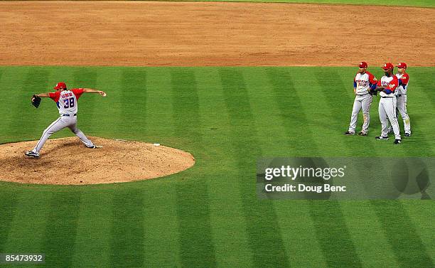 Pitcher Fernando Cabrera of Puerto Rico warms up to pitch in the ninth inning as teammates Felipe Lopez, Mike Aviles and Carlos Delgado watch while...