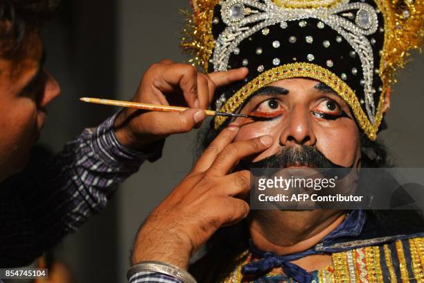 An Indian artist dressed as Ravan gets his make-up done before performing the 'Ramleela', the story of Lord Rama, ahead of the Hindu festival of...