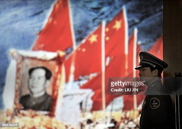 Security guard stands in front of a giant picture displayed at the 50th Anniversary of Democratic Reforms in Tibet Exhibition in Beijing on March 18,...
