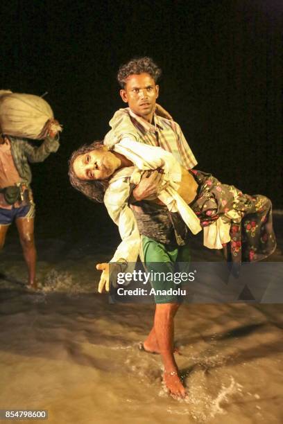 Rohingya man, fled with others from oppression within ongoing military operations in Myanmars Rakhine state, carries a woman in bad health condition,...