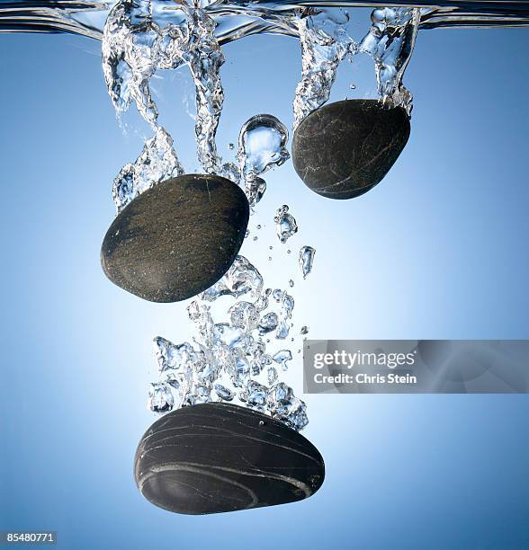 rocks splashing into water - sinking stockfoto's en -beelden
