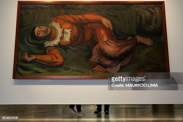Couple of visitors look at paintings behind the painting 'Mujer dormida - La primavera ', by Mexican artist David Alfaro Siqueiros part of the...
