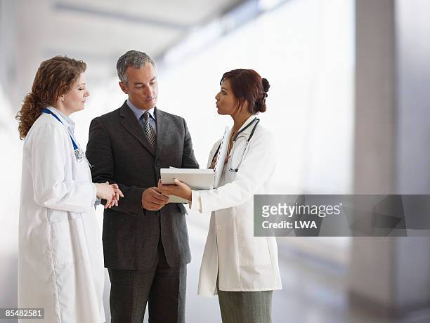 doctors talking to hospital administrator - medical protective suit stock pictures, royalty-free photos & images